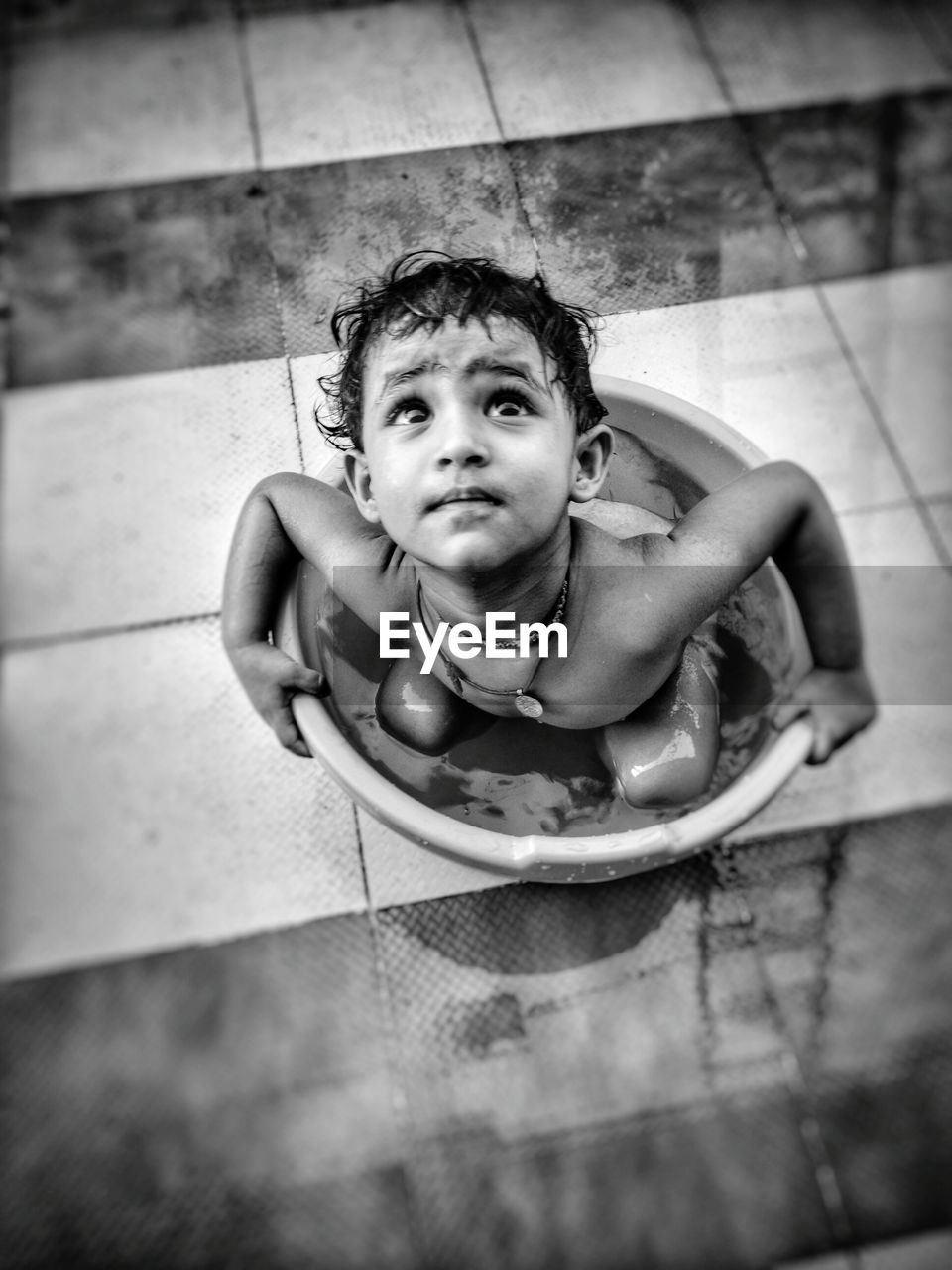 High angle view of shirtless boy in bucket