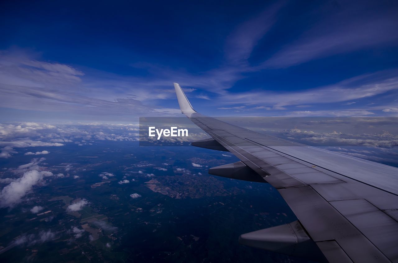 Airplane flying over landscape against blue sky