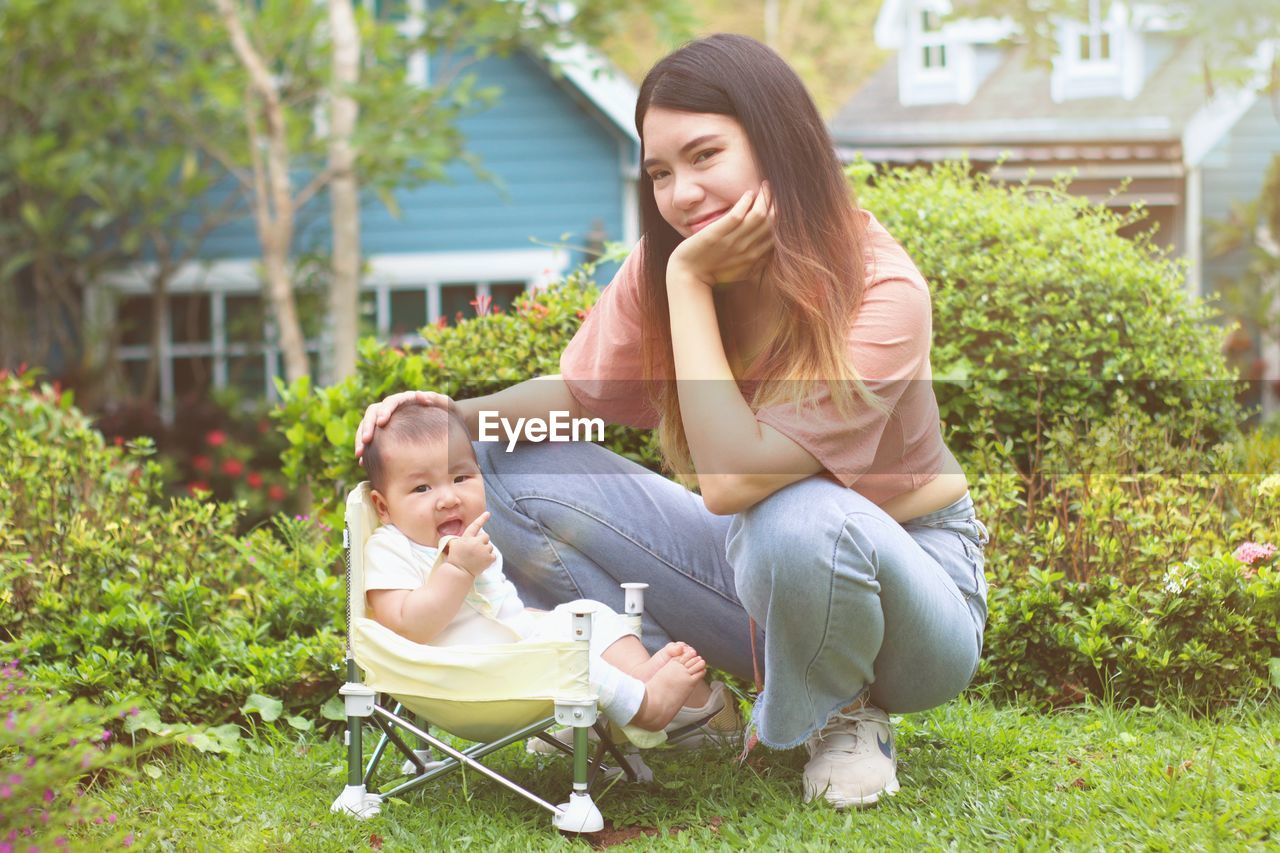 Happy young woman with baby sitting on plants