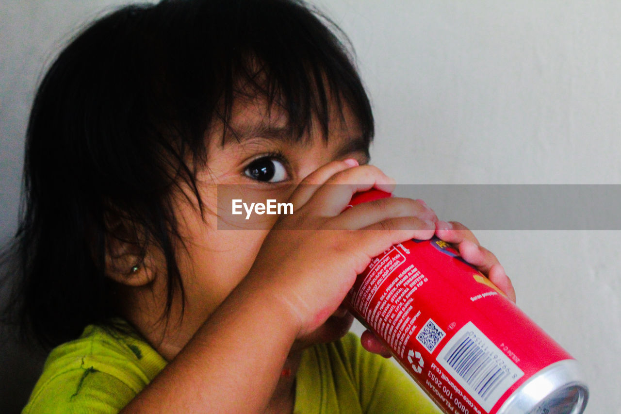 CLOSE-UP PORTRAIT OF CUTE BOY HOLDING RED EYES