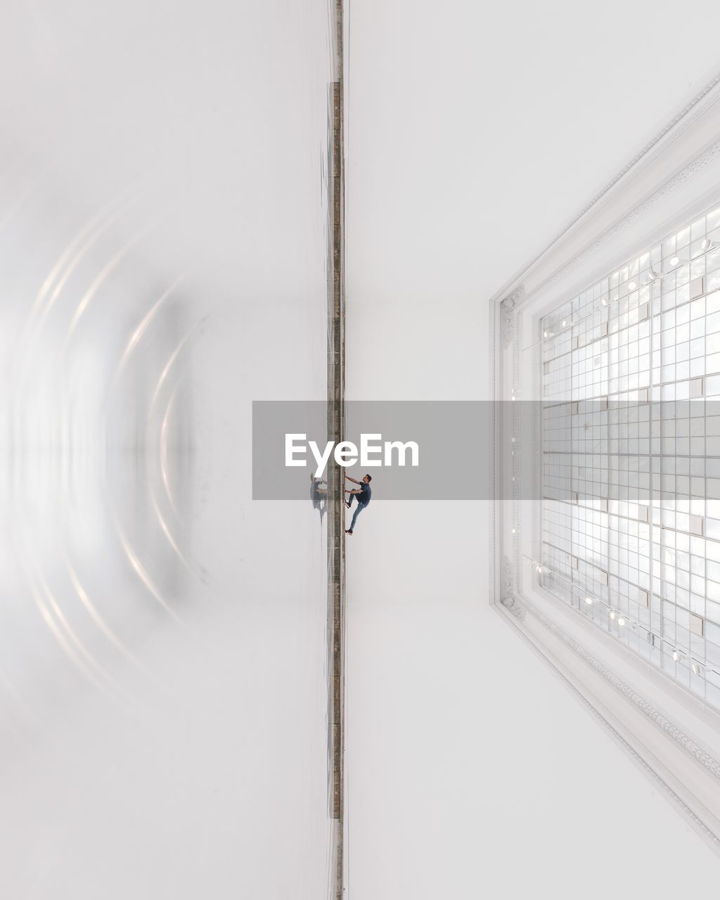 Tilt image of man reflecting on tiled floor