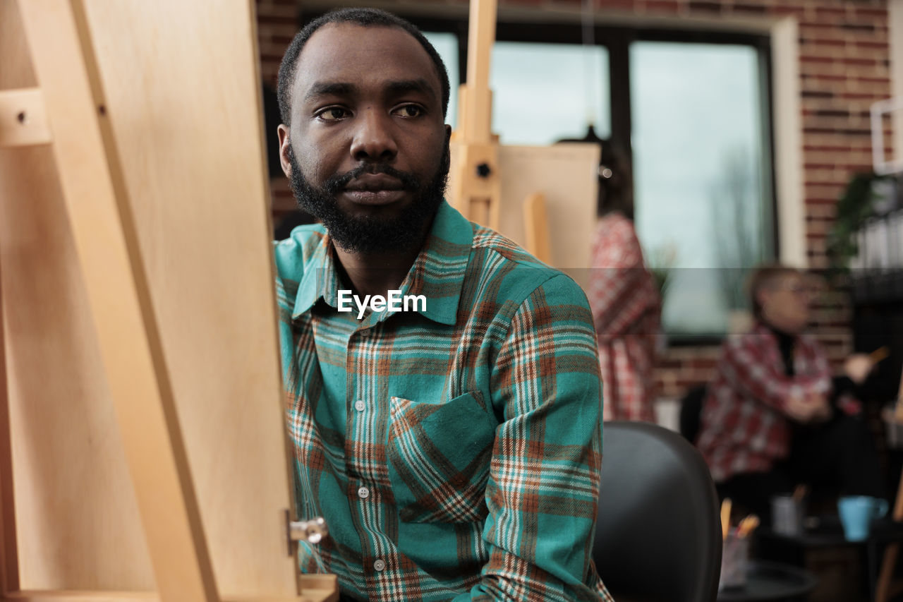 portrait of young man looking away while sitting at home