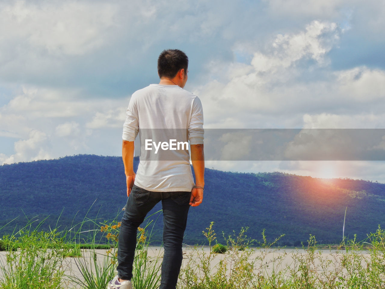 REAR VIEW OF MAN LOOKING AT FIELD