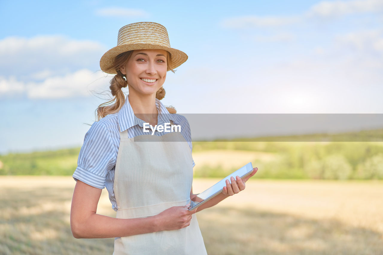 PORTRAIT OF A SMILING YOUNG WOMAN WEARING HAT