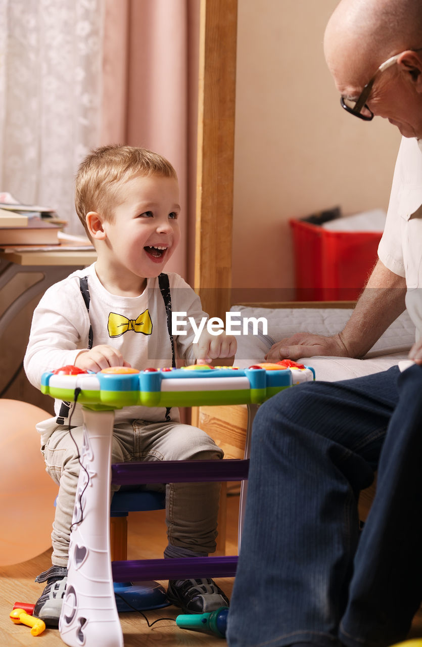 Grandson and grandfather playing with toy at home