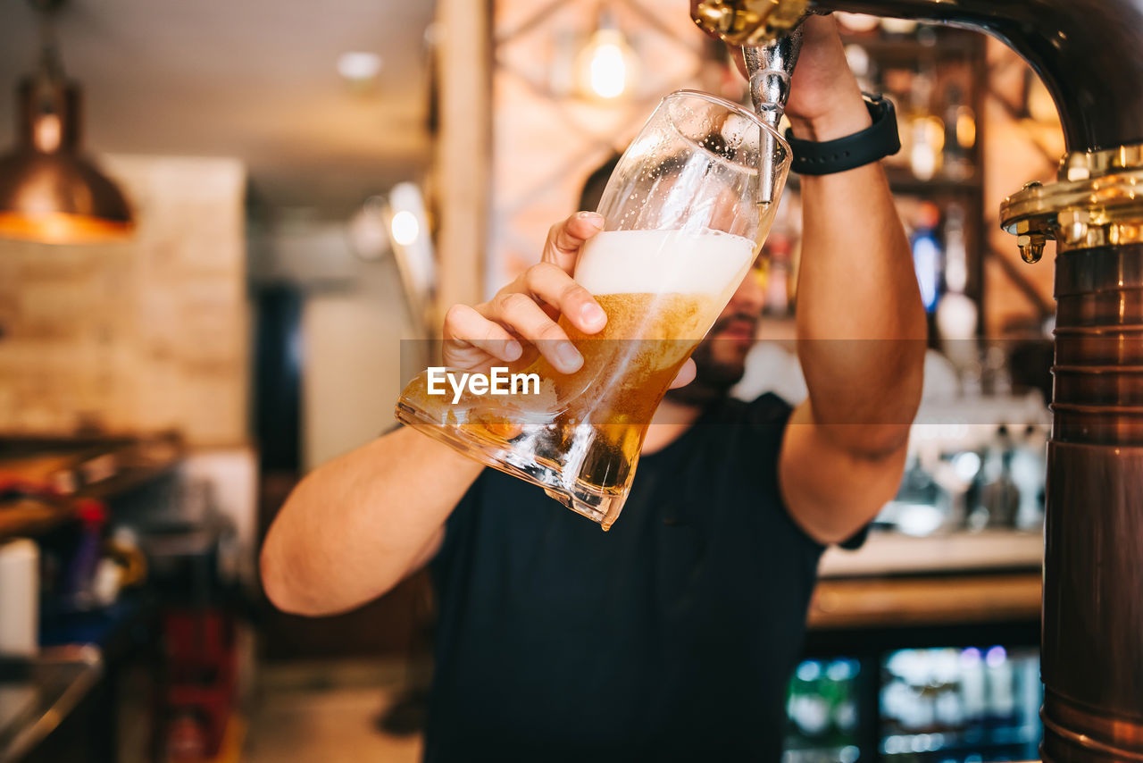 CROPPED IMAGE OF WOMAN HOLDING BEER GLASS AT BAR COUNTER