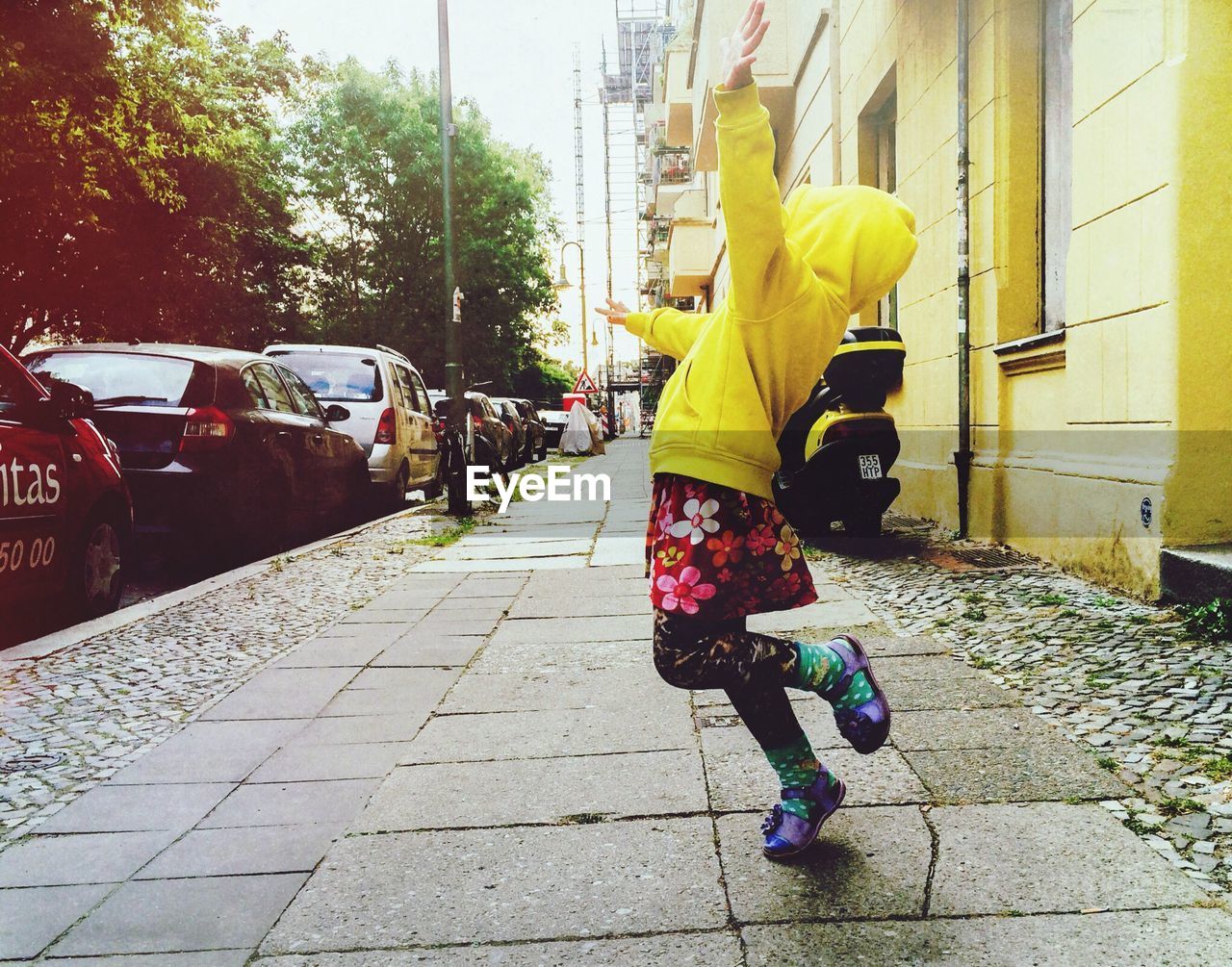 Full length of happy girl dancing on sidewalk