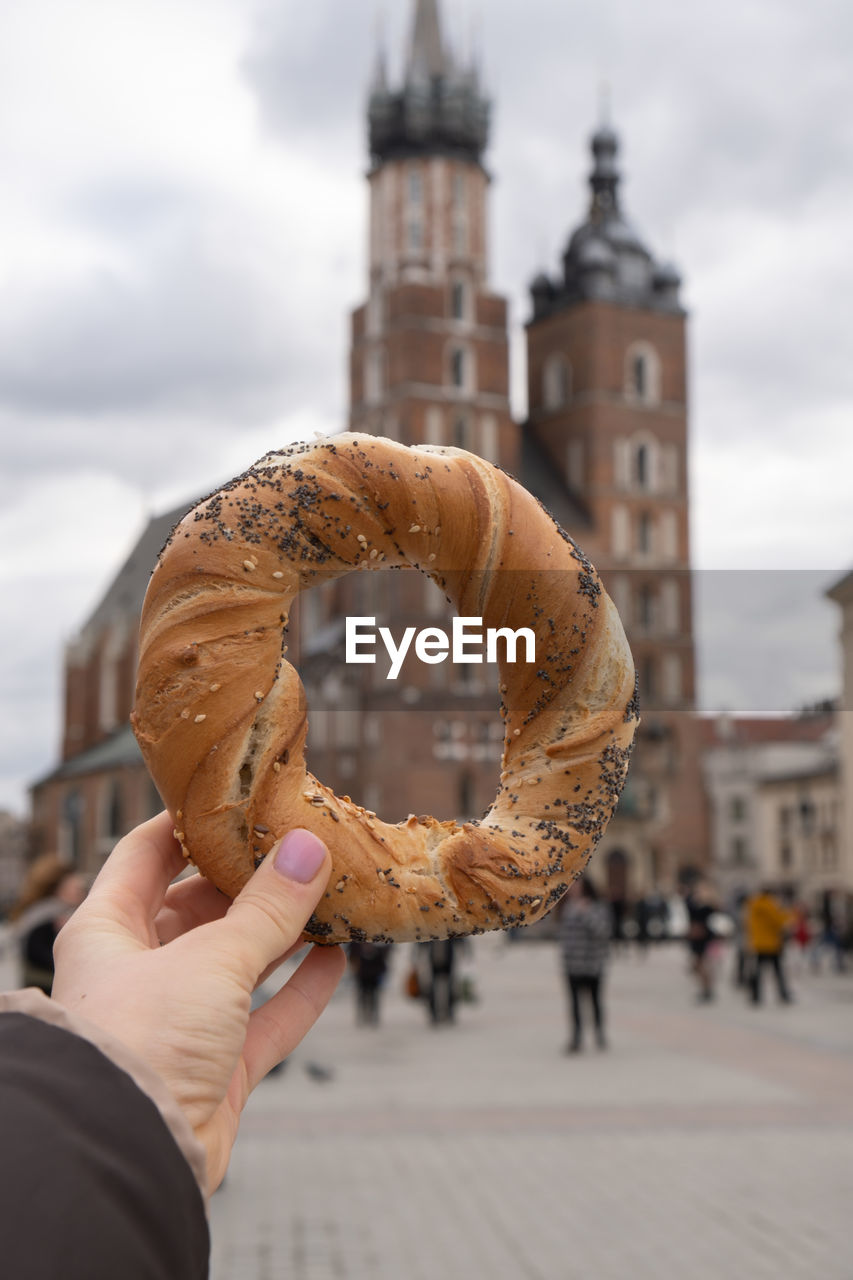 Tourist woman eating bagel obwarzanek traditional polish cuisine snack waling on market square st