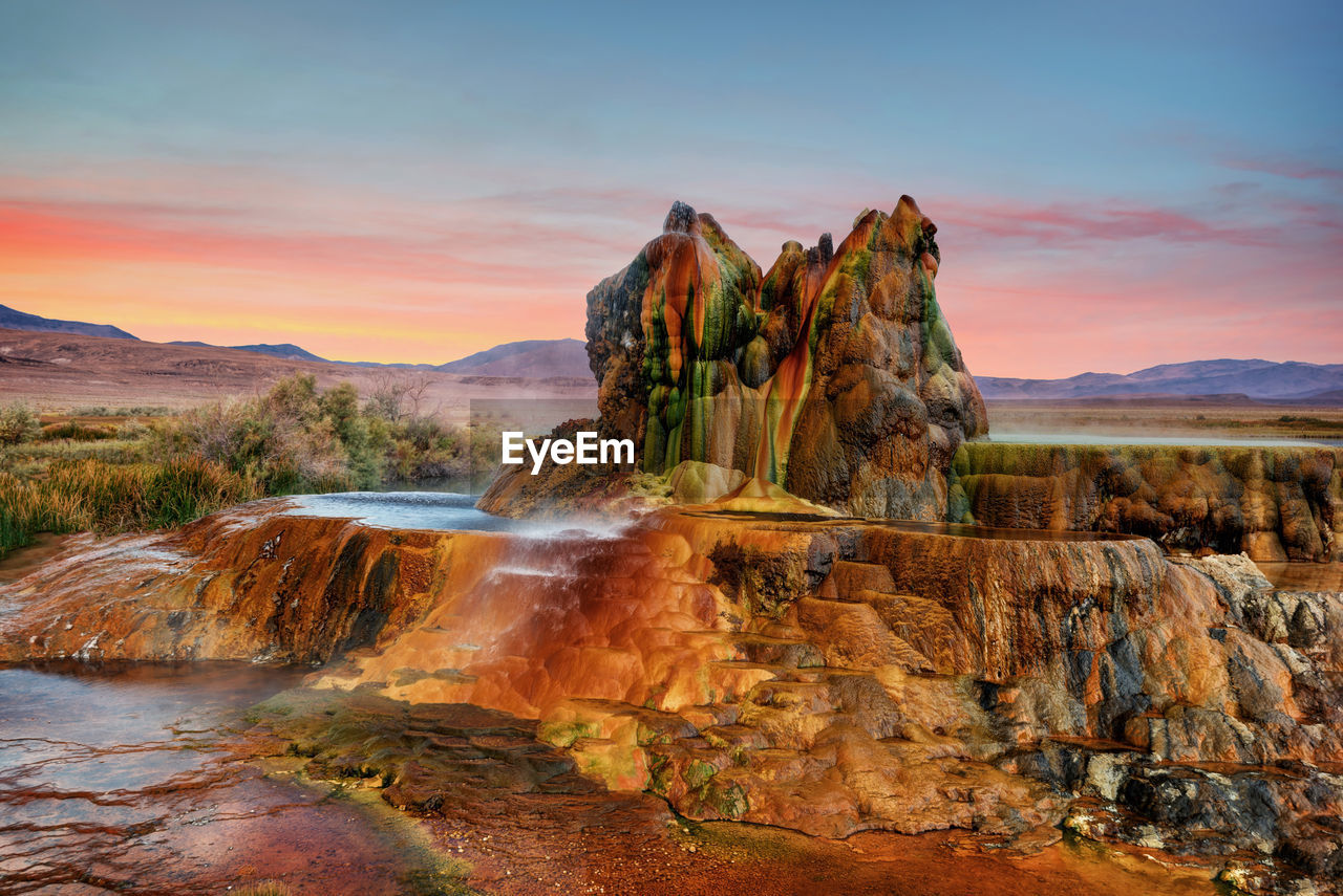 Rock formation on land against sky during sunset