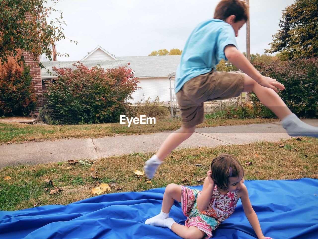 Playful boy jumping over sister in park