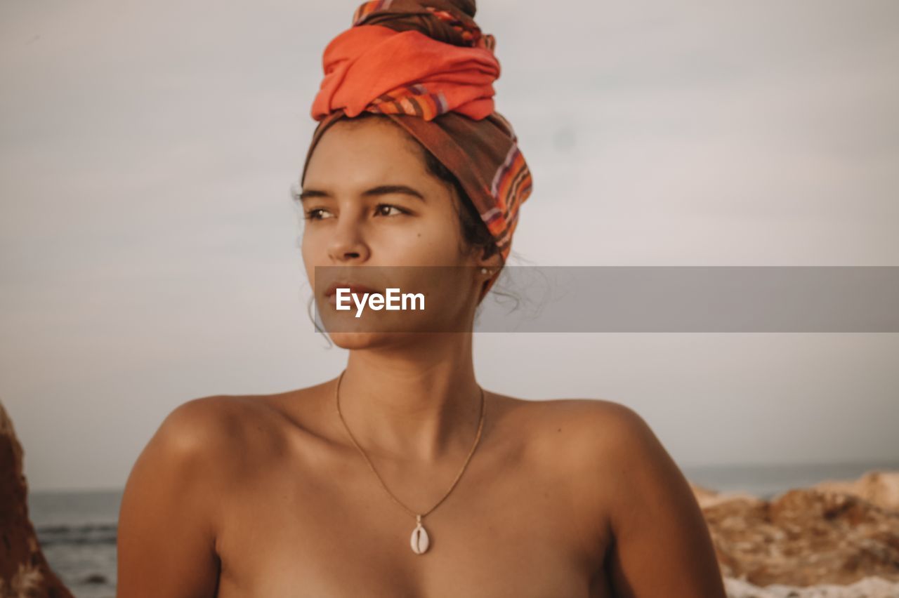 Woman looking away at beach against sky