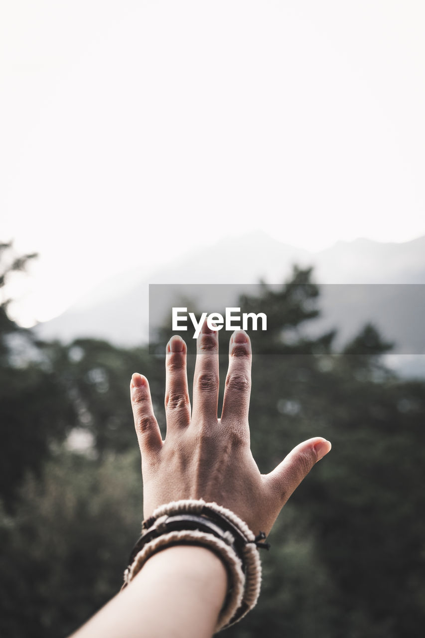 Cropped hand of woman showing stop gesture against trees