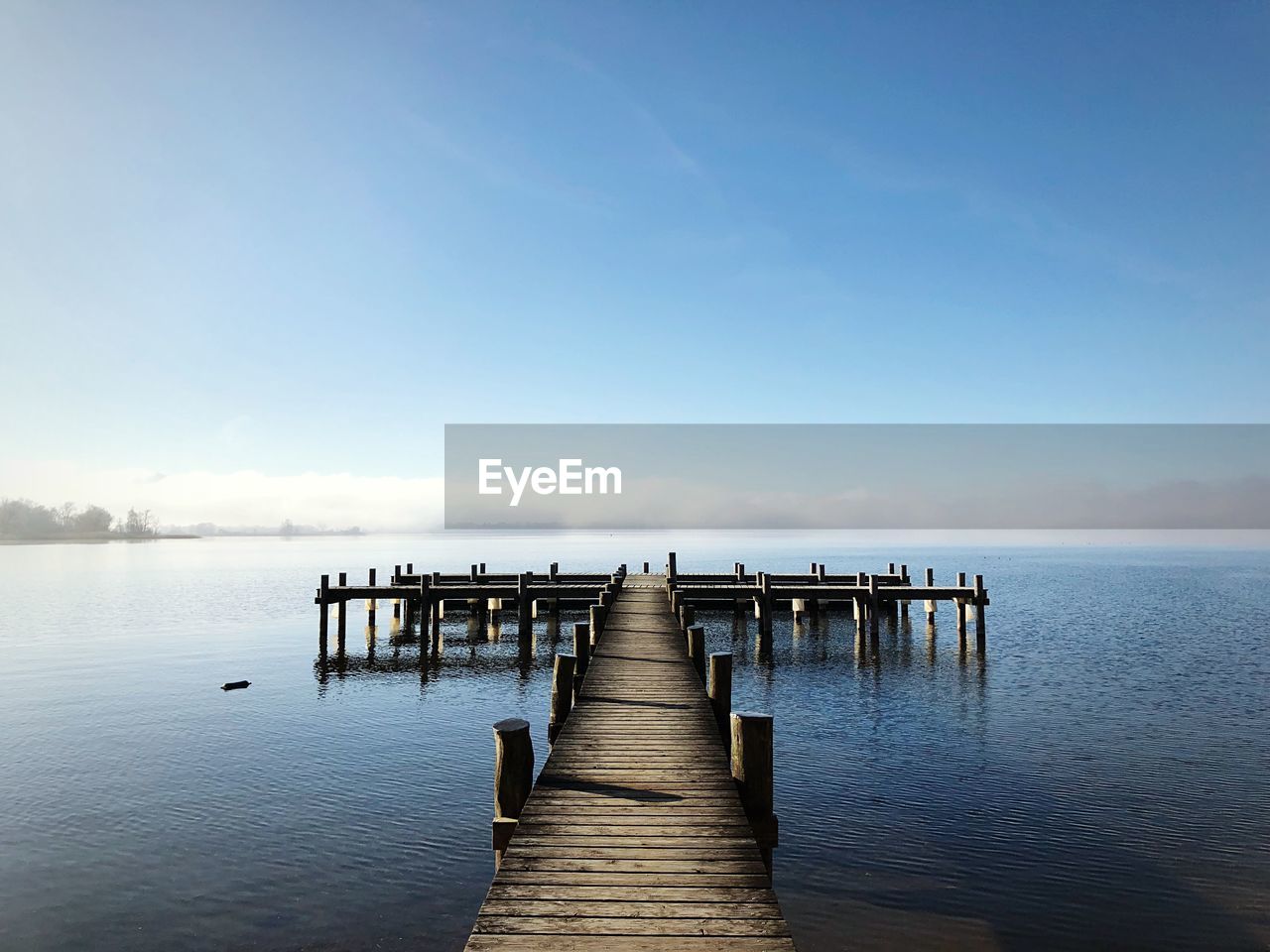 Pier over sea against clear blue sky