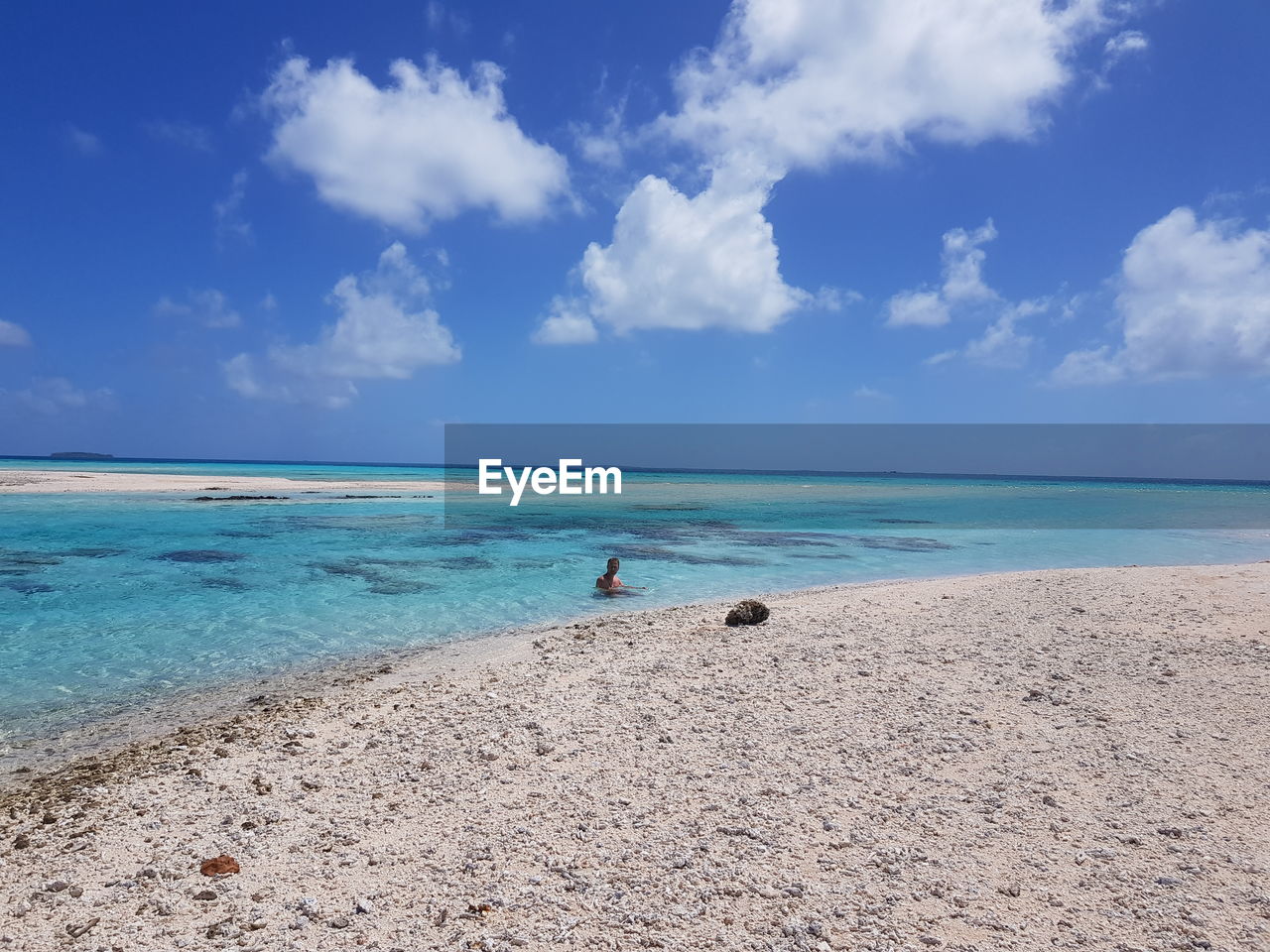 Man swimming in sea against cloudy sky