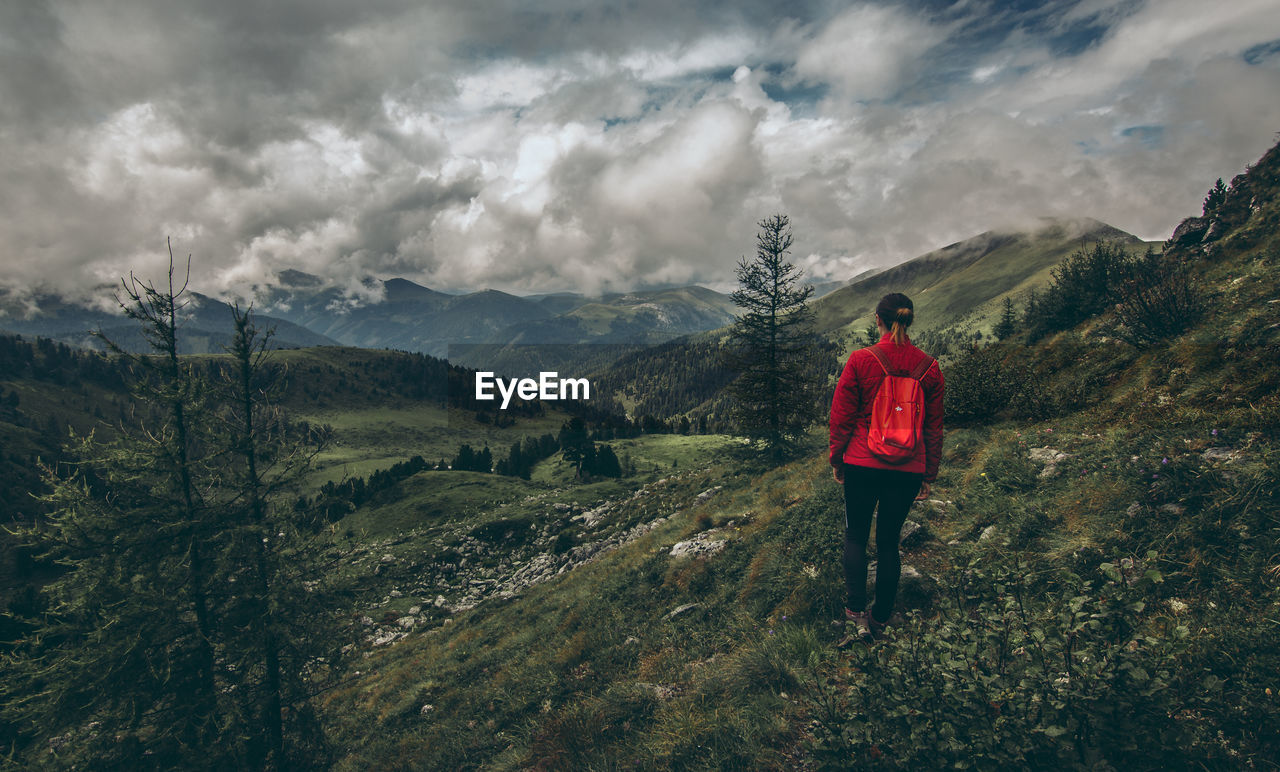 REAR VIEW OF MAN STANDING ON MOUNTAIN