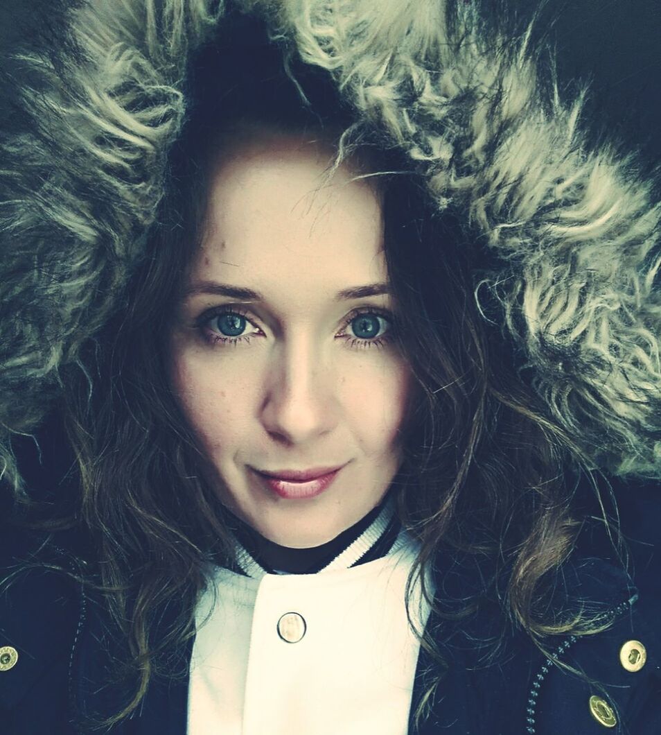 Close-up portrait of young woman in warm clothing against black background