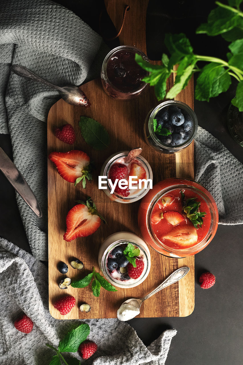 food and drink, food, healthy eating, fruit, freshness, herb, berry, vegetable, wellbeing, high angle view, red, wood, no people, directly above, produce, indoors, strawberry, tomato, rustic, household equipment, ingredient, leaf, spice, studio shot, plant, cutting board, still life, meal, drink, plant part, table, refreshment, glass, basil, drinking glass, dark, alcohol