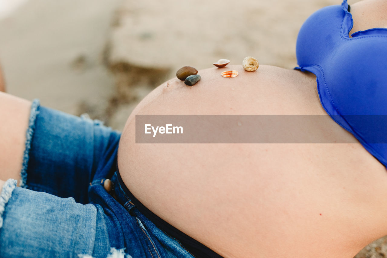Midsection of pregnant woman at beach
