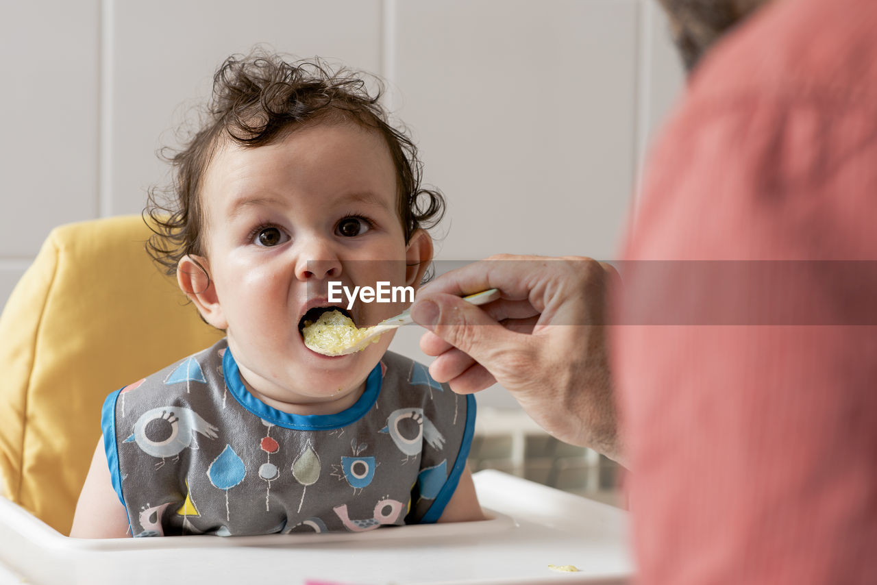 Expressive boy child eating some baby food for lunch.