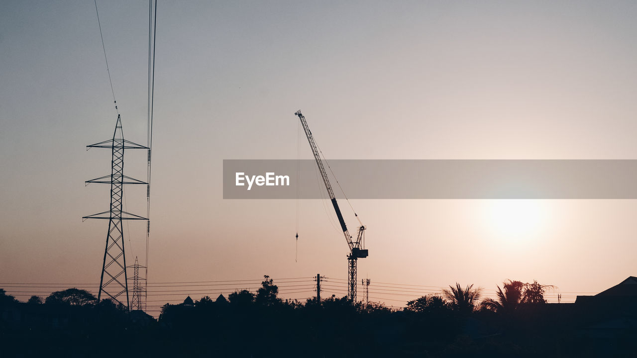 Low angle view of silhouette cranes against sky during sunset