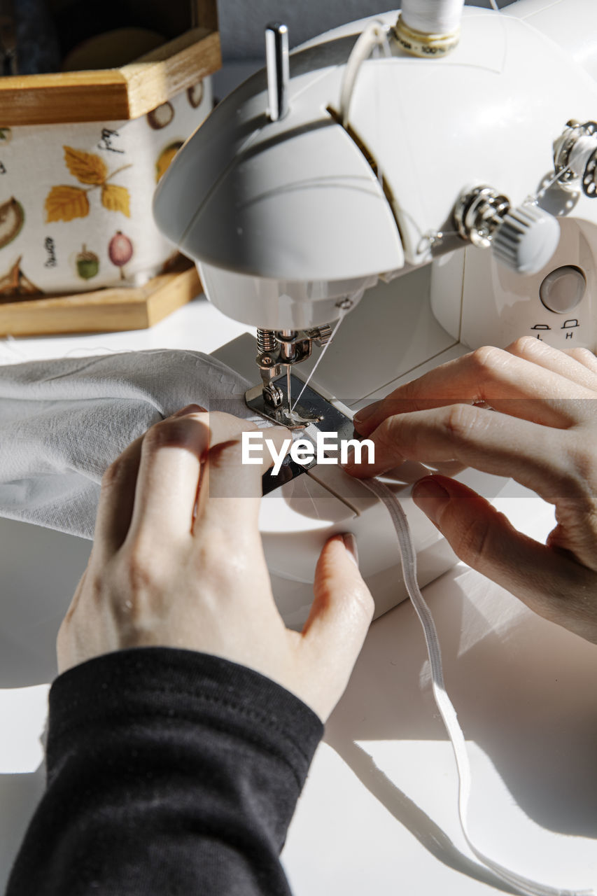 Crop seamstress using sewing machine in workshop