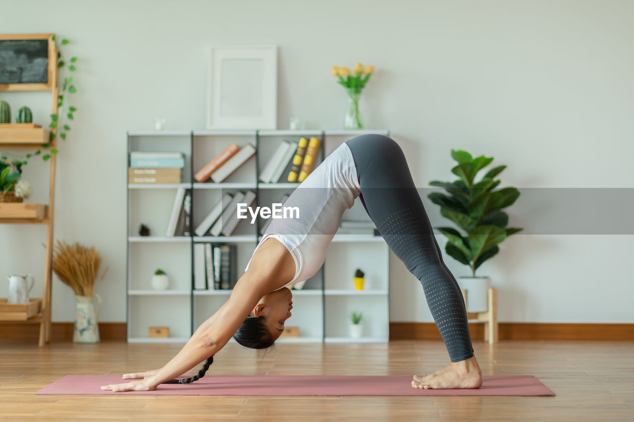 Midsection of woman with arms raised on floor at home