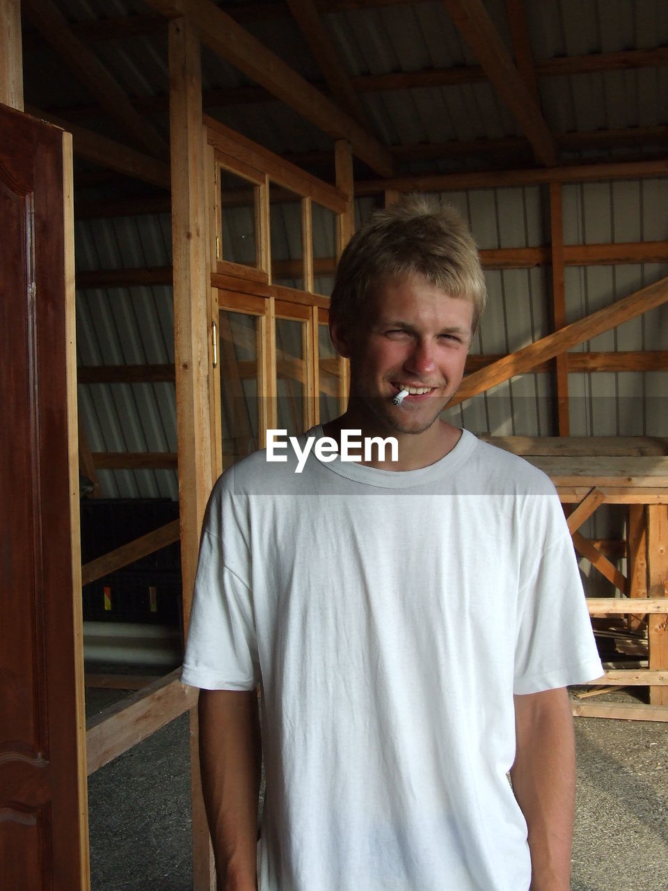 Portrait of smiling smoking man standing at home