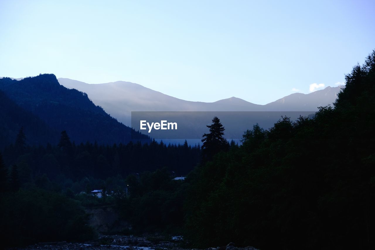 mountain, tree, nature, scenics - nature, sky, wilderness, beauty in nature, forest, plant, environment, mountain range, land, landscape, coniferous tree, pinaceae, pine tree, tranquility, tranquil scene, lake, no people, blue, pine woodland, non-urban scene, water, silhouette, morning, outdoors, travel destinations, travel, reflection, snow, idyllic, woodland, clear sky