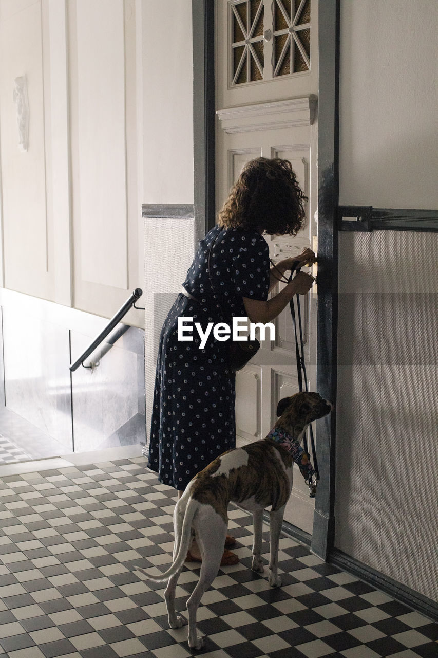 Woman locking house door while standing with dog