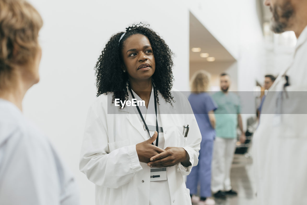 Mature female doctor discussing with colleagues at hospital