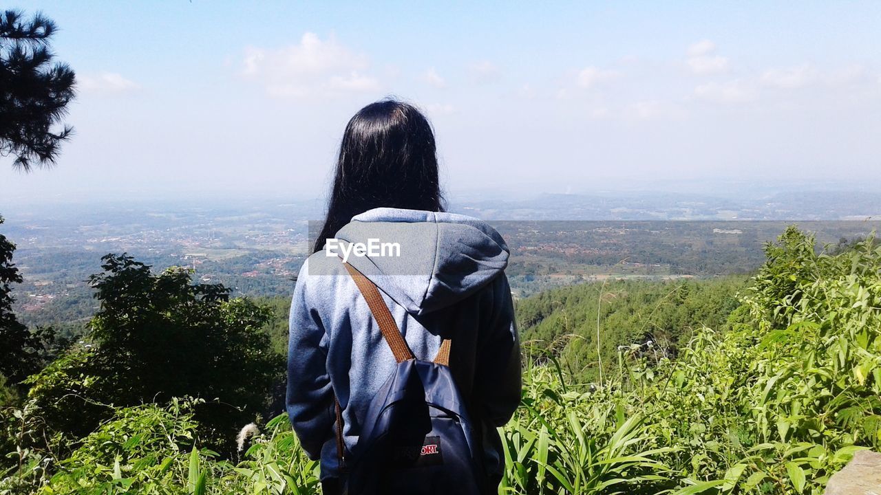 Rear view of woman looking at landscape against sky