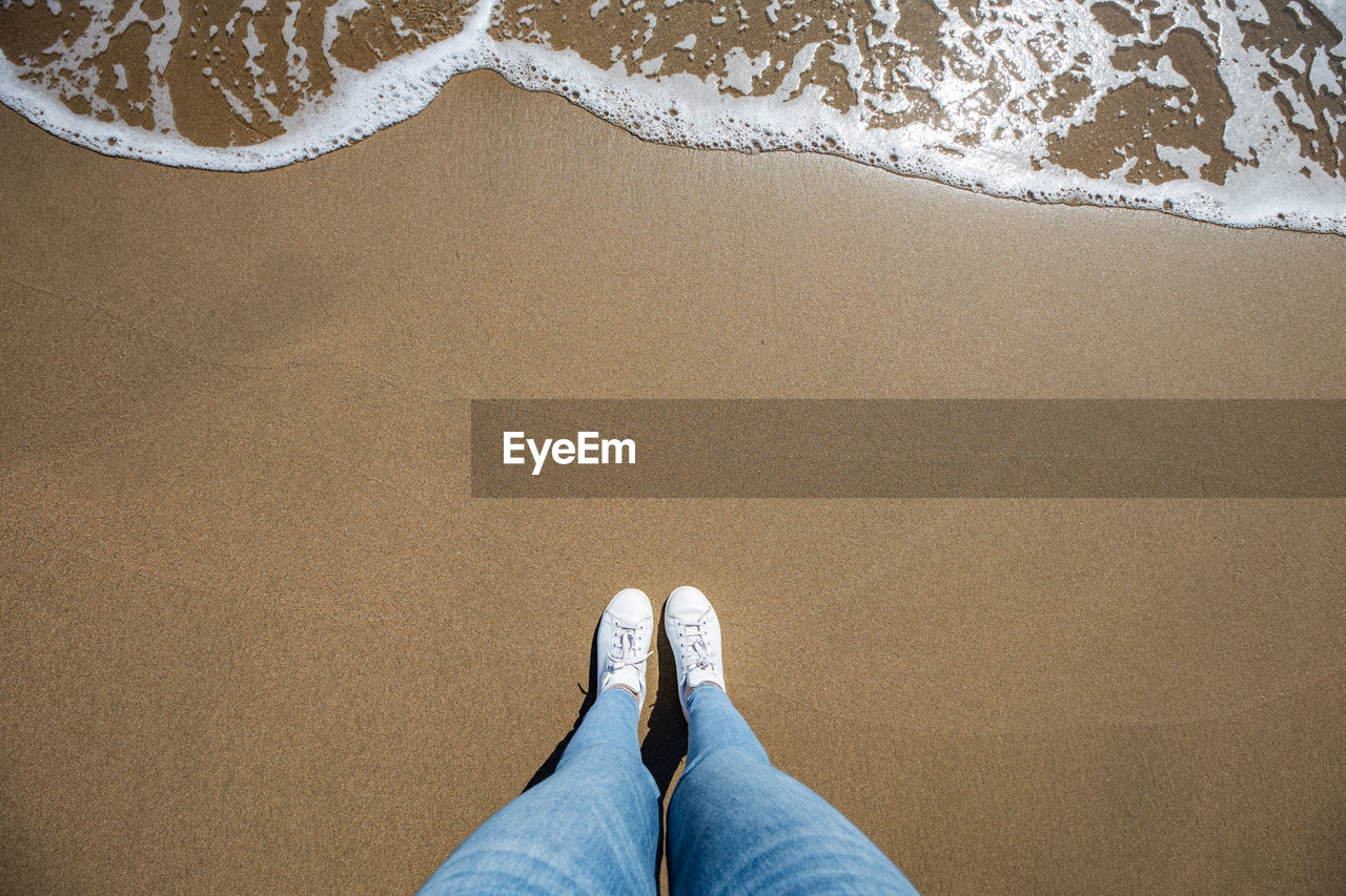 Low section of woman standing at beach