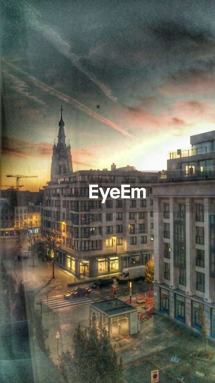 BUILDINGS IN CITY AGAINST CLOUDY SKY AT DUSK