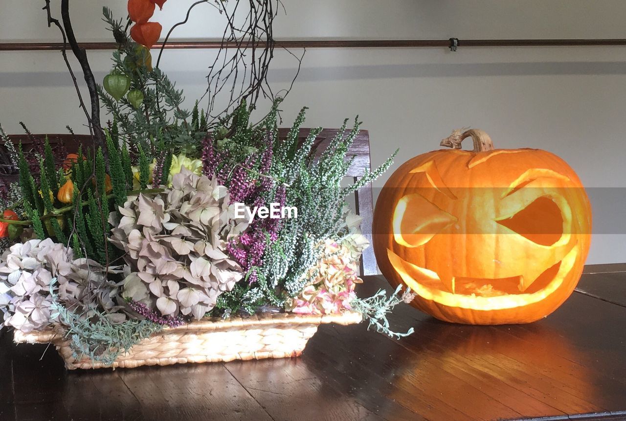 VARIOUS FLOWERS ON TABLE AGAINST WALL