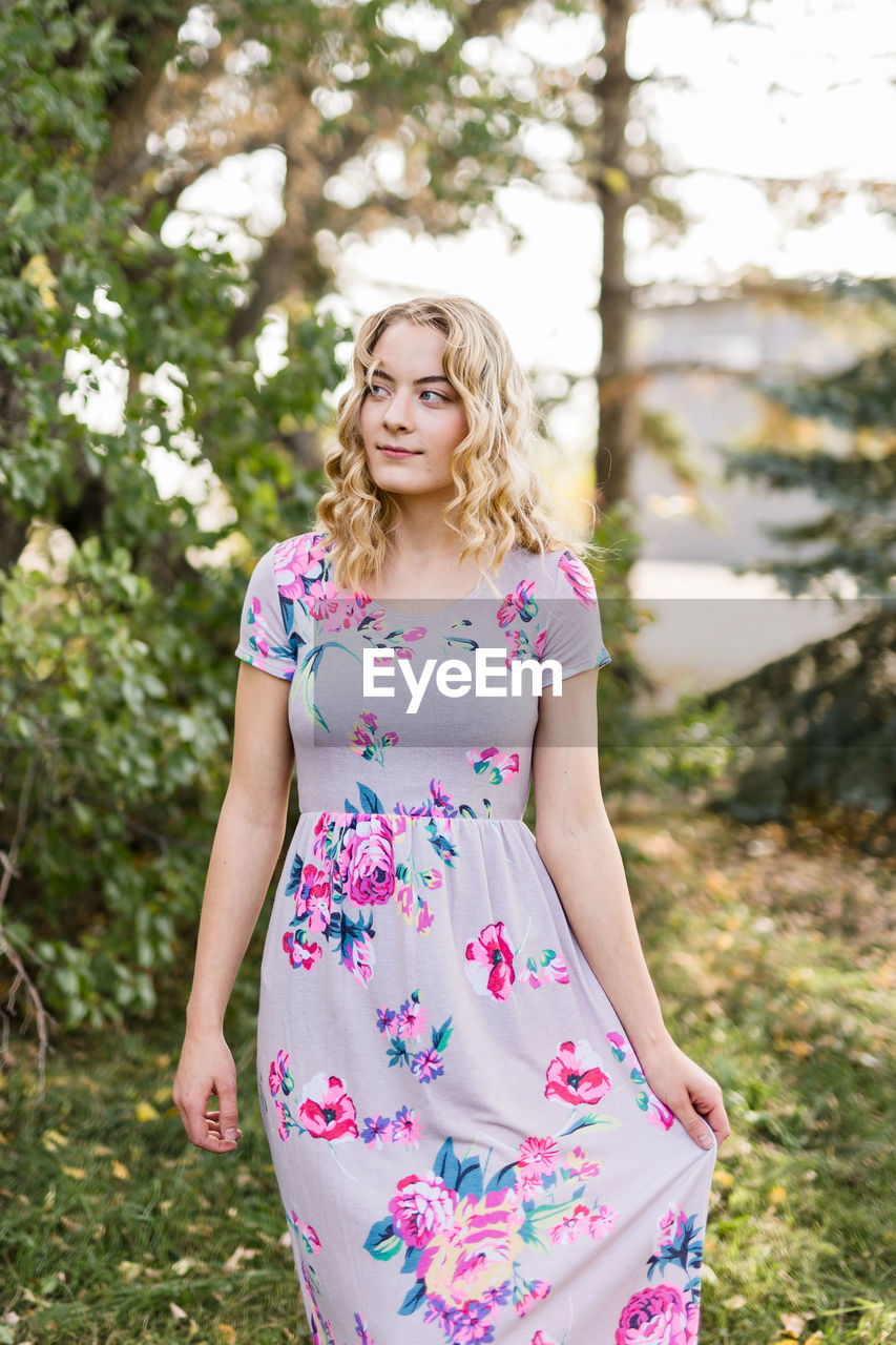 Portrait of young woman standing against trees