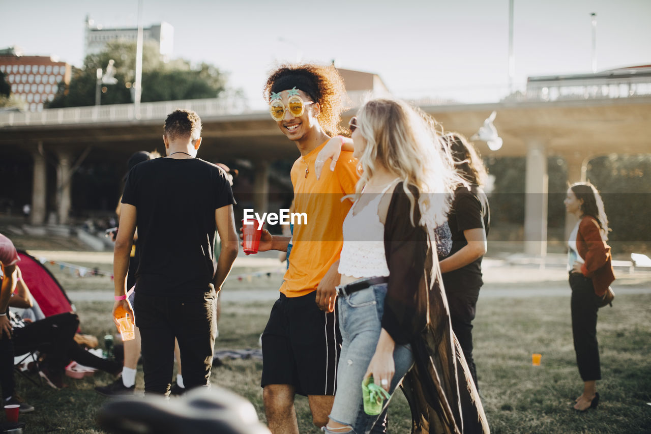 Smiling man and woman talking with friends in background