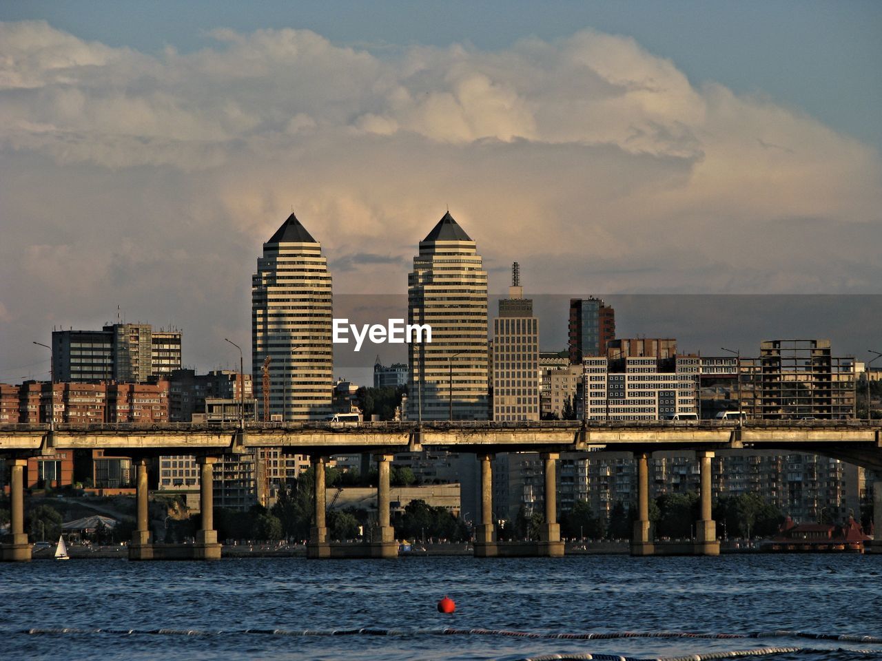 Sea by cityscape against sky during sunset