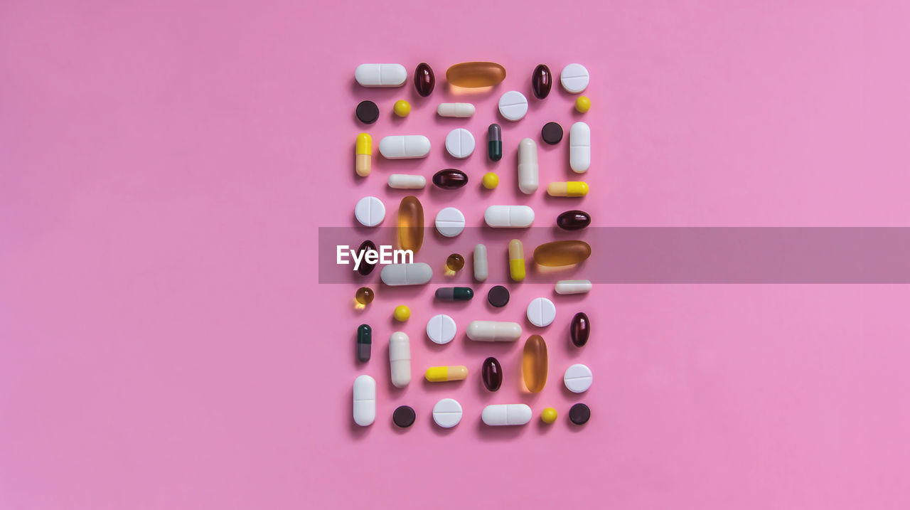 Different types of pills lie on a pink background, medicine treatment, vitamins, antibiotic