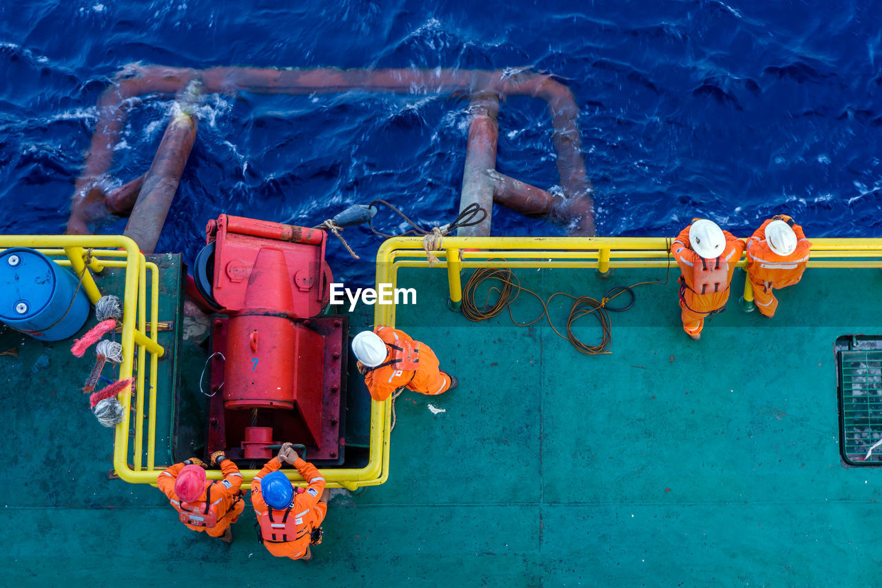 High angle view of workers standing on boat in sea
