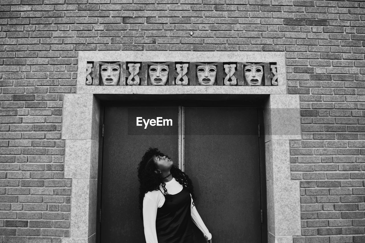 GIRL STANDING AGAINST BRICK WALL