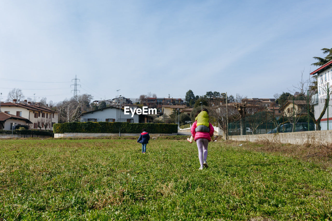 Rear view of children walking on field