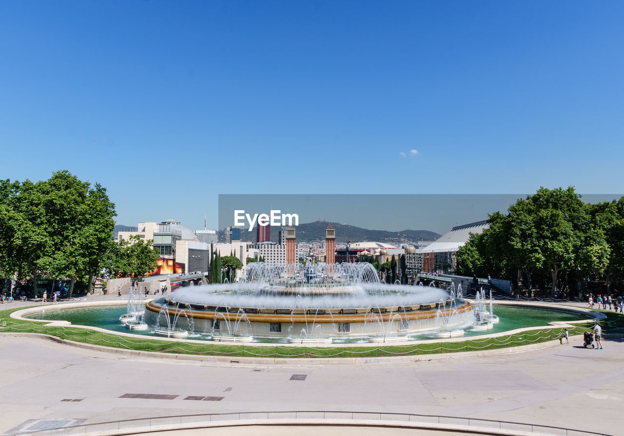 FOUNTAIN BY BUILDINGS AGAINST BLUE SKY