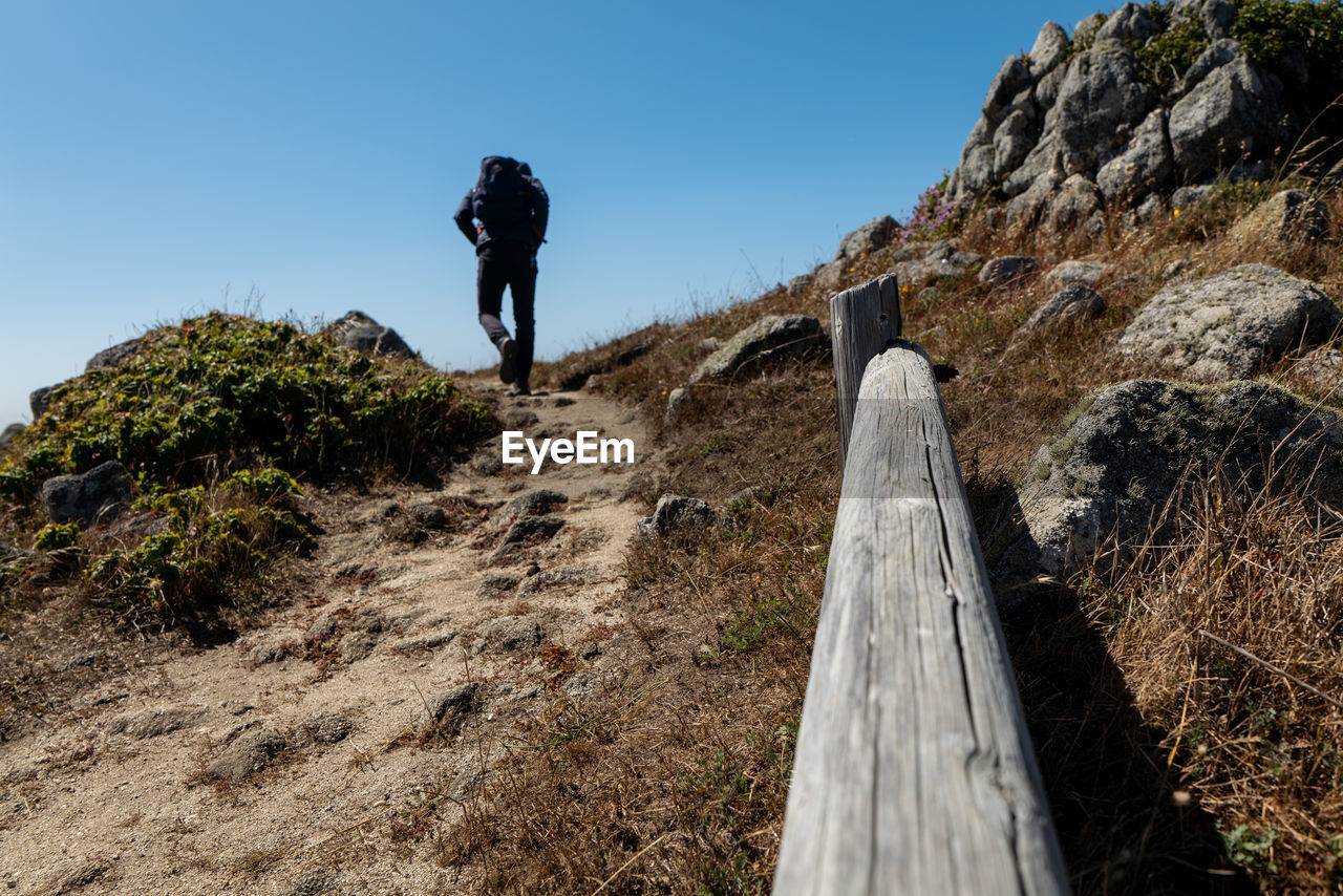 Hiker walking up hill on coastal trail in california with blue sky