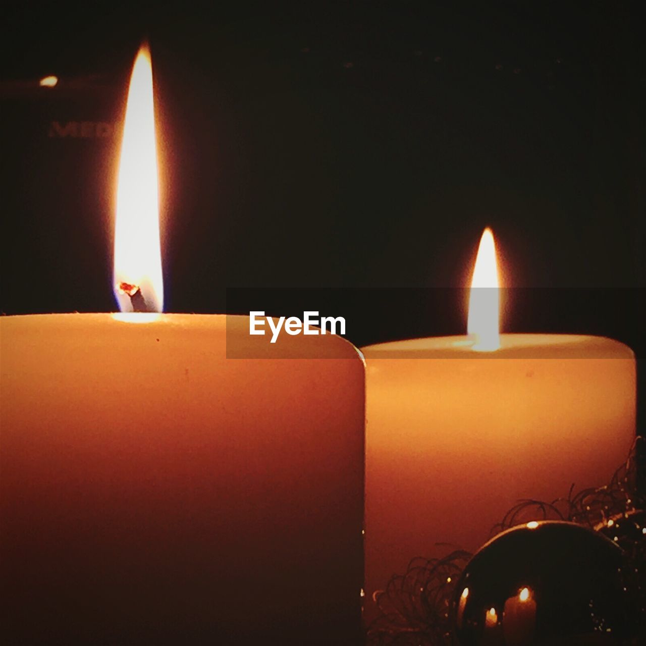 CLOSE-UP OF LIT TEA LIGHT CANDLES IN DARK ROOM