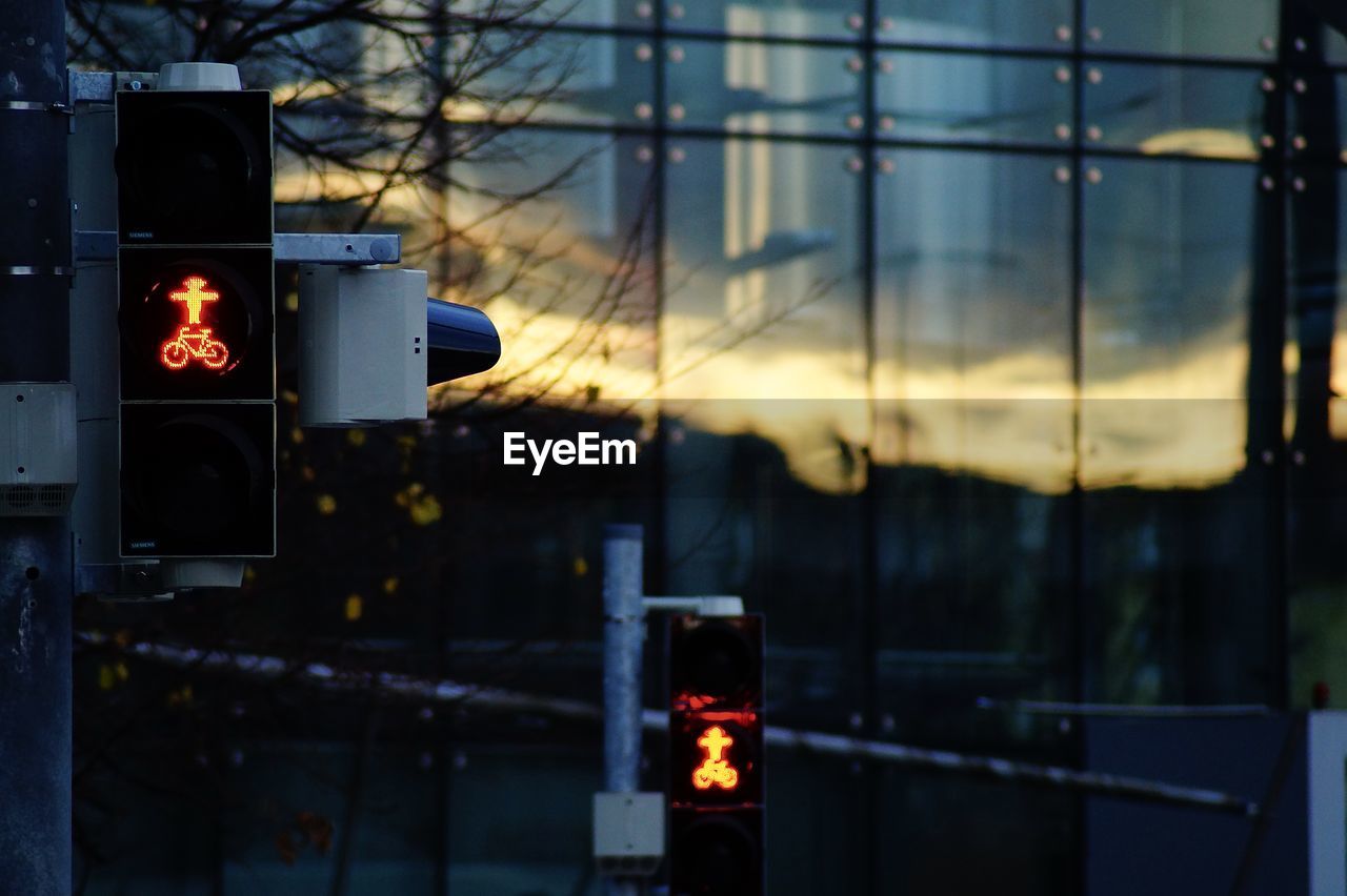 Illuminated road sign against sky at sunset