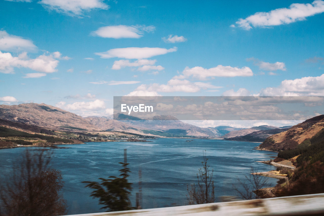 SCENIC VIEW OF SEA BY MOUNTAINS AGAINST SKY