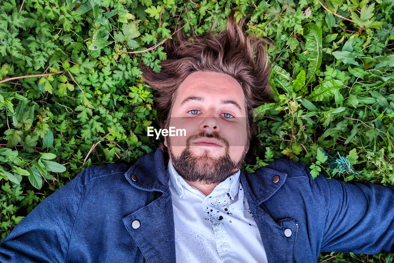 Portrait of man lying on plants
