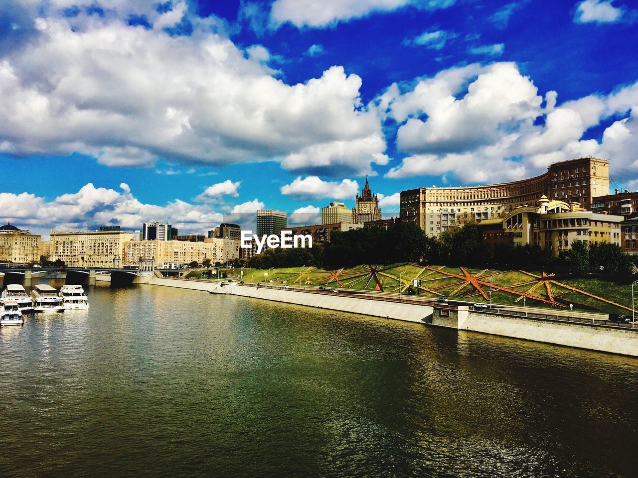 VIEW OF RIVER AND CITYSCAPE AGAINST CLOUDY SKY