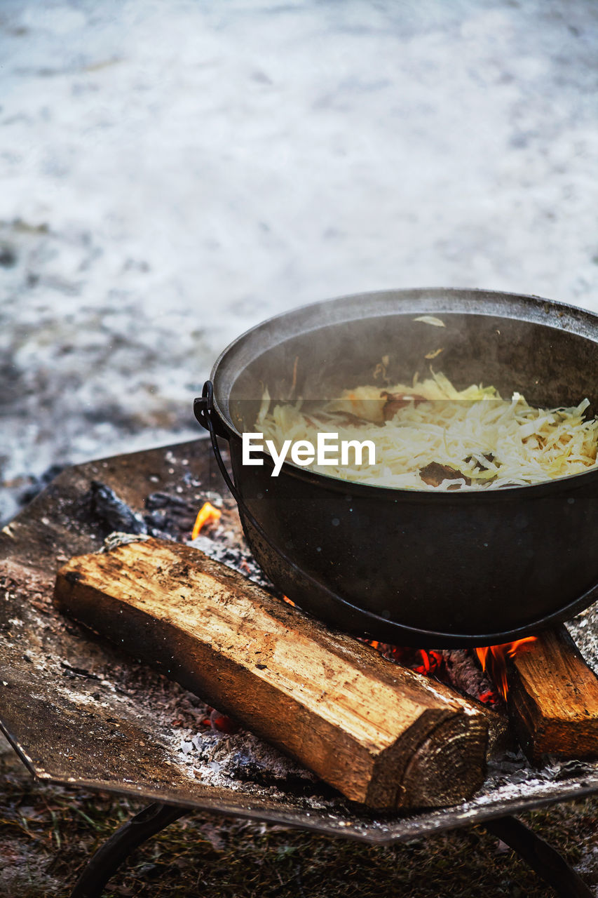 Cabbage with meat cooking in a cauldron on open fire during a festival in winter.