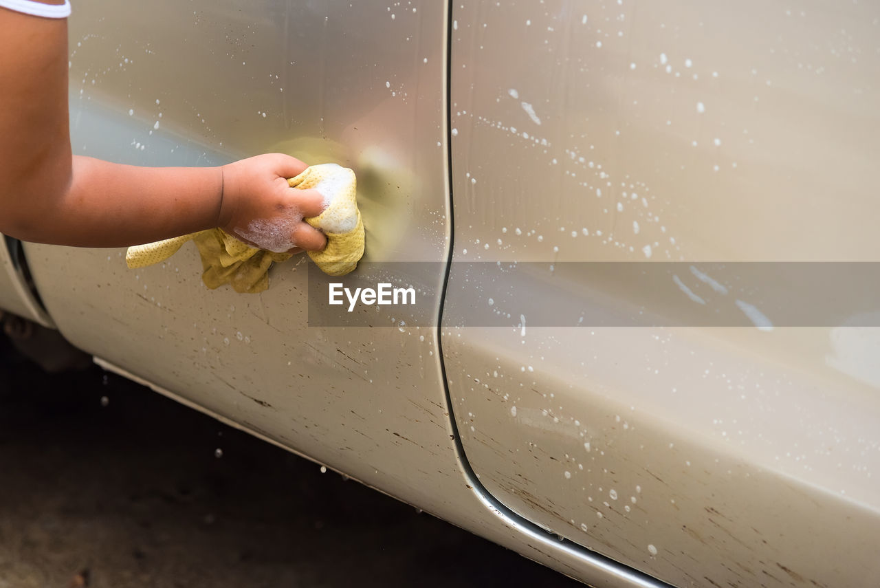 Cropped hand of woman cleaning car